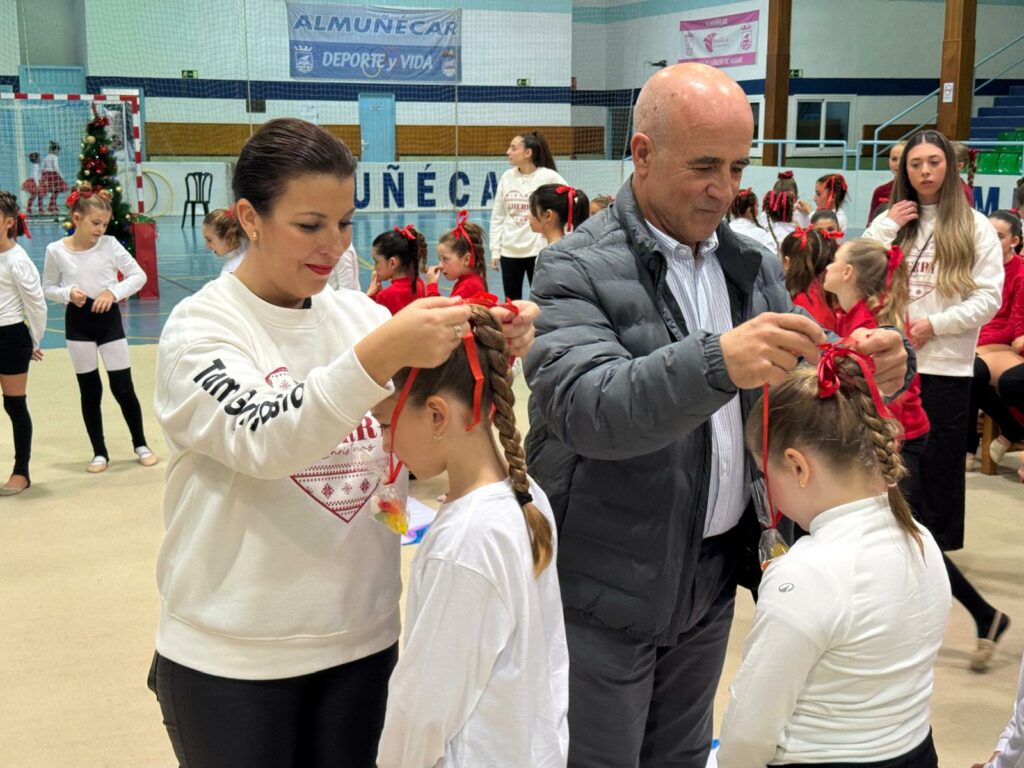 La coordinadora de la escuela y el concejal de deportes de Almuñécar ponen las medallas dulces a las gimnastas